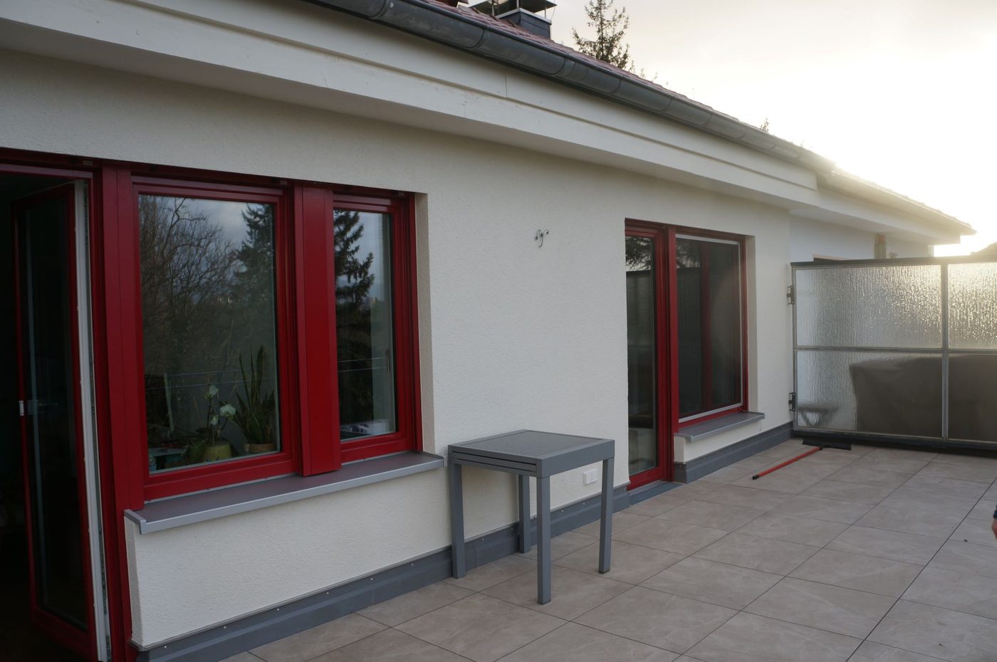 Erweitertes Wohnhaus mit roten Fenstern und Dachterrasse