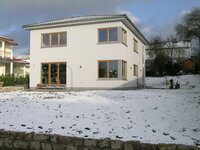 Weißes Einfamilienhaus mit Zeltdach im Schnee